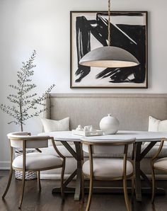 a dining room table with four chairs and a large painting on the wall above it