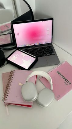 an open laptop computer sitting on top of a desk next to headphones and notebook