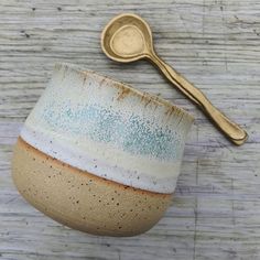 a white and blue bowl with a gold spoon on the side, sitting next to it