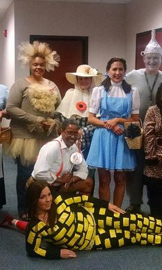 a group of people dressed in costumes posing for a photo with a snake on the floor