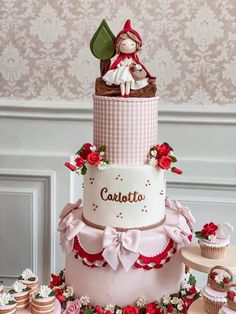 a three tiered cake with cupcakes and decorations on the table next to it