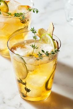 two glasses filled with lemonade and garnish sitting on a marble counter top