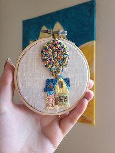 someone is holding up a small embroidery art piece