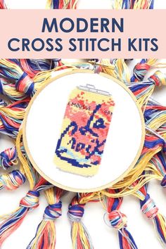 the modern cross stitch kit is displayed on a white surface with colorful yarns around it