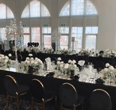 a long table set up with black chairs and white flowers