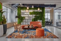 an office lobby with plants growing on the wall and couches in front of it