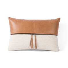 a tan and white pillow with tassels on it