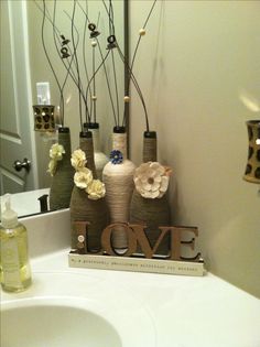 some vases with flowers are sitting on a bathroom counter