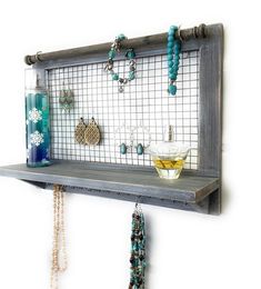 a wooden shelf with jewelry hanging from it's sides and a glass vase on the other side