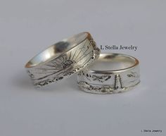 two silver rings with designs on them sitting next to each other in front of a white background