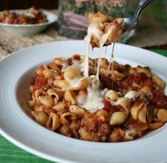 a plate with pasta and sauce being drizzled over it's top