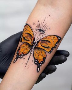 a butterfly tattoo with an eye on it's back arm and the wings are yellow