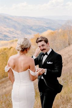 a man in a tuxedo adjusting the tie of his bride's dress