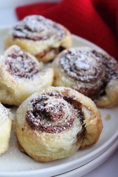 cinnamon rolls on a white plate with powdered sugar sprinkled on the top