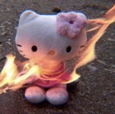 a hello kitty doll sitting on the ground with fire coming out of it's mouth