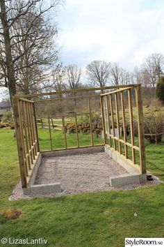 a wooden structure sitting on top of a lush green field