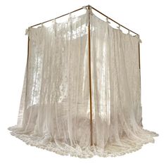 a white bed with sheer curtains hanging from it's sides