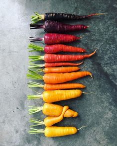 a bunch of different colored carrots lined up on top of each other in a row