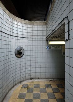 an empty public bathroom with checkered tile flooring and round mirror on the wall