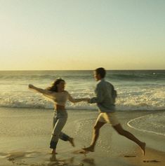 two people running on the beach near the ocean