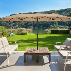 an outdoor patio with chairs, tables and umbrellas on the deck overlooking a lush green field