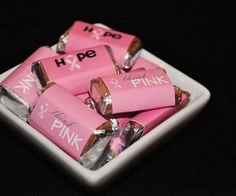 pink candy wrapped in foil sitting on top of a white square plate with the word h p e