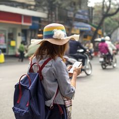 a woman in a hat is looking at her cell phone while walking down the street