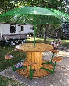 a wooden table with an umbrella attached to it in front of a camper trailer