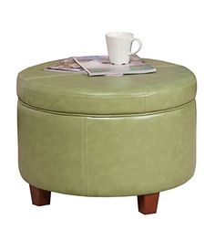 a green ottoman sitting on top of a table next to a cup and saucer