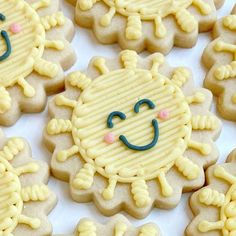 decorated cookies with smiley faces are on a white tablecloth covered in blue and yellow icing