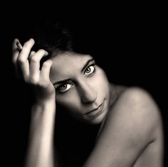 a black and white photo of a woman with her hand on her head looking at the camera