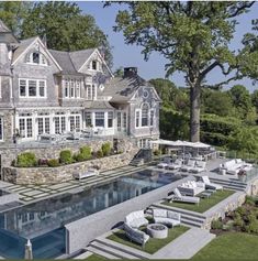 an aerial view of a large house with a pool in the front yard and lounge chairs around it