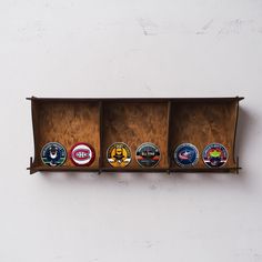 four different types of beer bottle caps in a wooden case on a white wall background