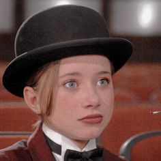 a woman wearing a top hat and bow tie looking at the camera with an intense look on her face