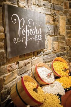 several buckets filled with food sitting next to a sign that says popcorn bar on it