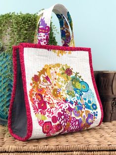 a colorful handbag sitting on top of a table next to a potted plant