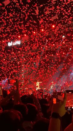 a large group of people at a concert with confetti falling from the ceiling