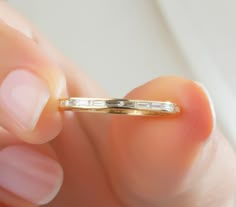 a woman's hand holding a gold ring with three baguettes on it