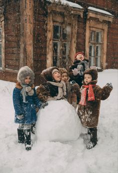 four children standing around a snowman in the snow