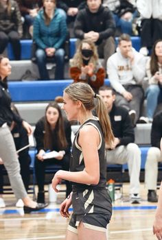 a girl is playing basketball in front of an audience at a game with other people watching