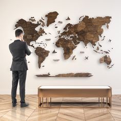 a man standing in front of a wooden world map