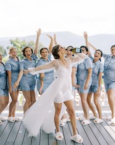 a group of women standing on top of a wooden floor next to each other holding their hands in the air