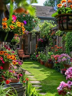 a garden filled with lots of flowers next to a wooden fence and green grass covered yard