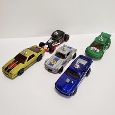 five toy cars lined up on a white surface