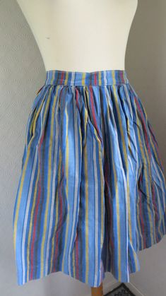 "Size Small. Skirt made between the the 20s to 50s with a cool striped pattern in the colors blue, yellow, black and red. It has a very antique look to it and the fabric is a bit course and could be handwoven. The look of the skirt is kind of 50s but I think the skirt could be much older, and maybe altered in the 50s. It does not have any fabric label, but it is cotton. It closes with a button at the backside and has two snap closures . It has a tear in the fabric at the end of the opening, but Retro Striped Skirt For Summer, Retro Striped Summer Skirt, Summer Retro Striped Skirt, Retro Blue Cotton Skirt, Vintage Blue Pleated Skirt, Vintage Blue Pleated Skirt Bottoms, Vintage Blue Full Skirt, Blue Lined Vintage Skirt, Vintage Blue Lined Skirt