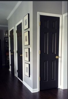 a black door in a room with pictures on the wall and wood flooring around it