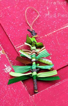 a small christmas tree made out of ribbon on top of a pink box with a tag hanging from it's side