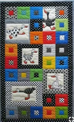 a quilted wall hanging with different colored squares and animals on the front, along with black polka dots