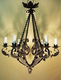 a chandelier hanging from the ceiling with lit candles in front of an artistic background