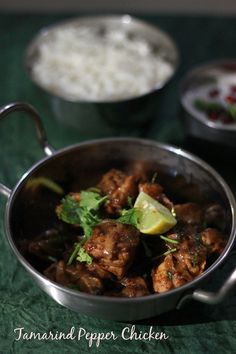 some food is in a metal pan on a green tablecloth with white rice and other dishes